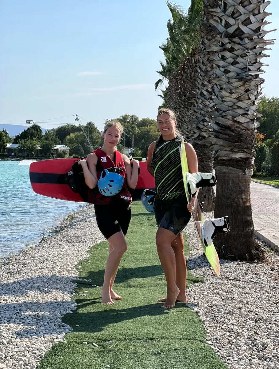Две участницы кэмпа с вейкбордами у воды
