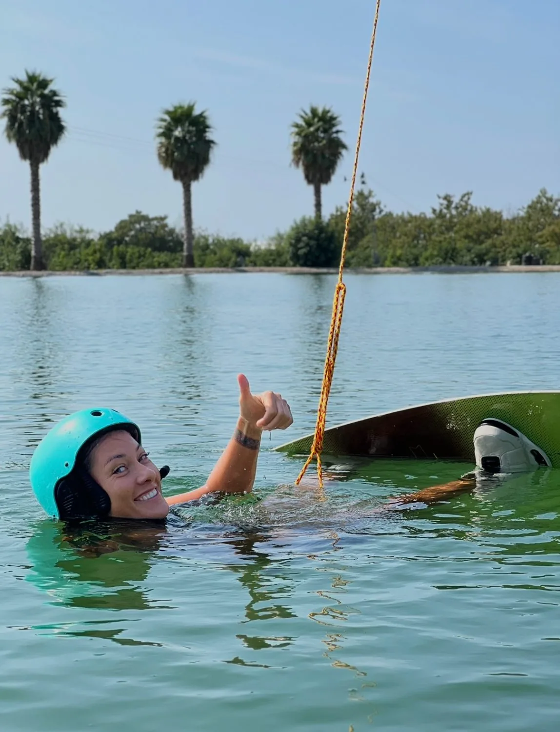 Участница кэмпа в воде рядом с доской